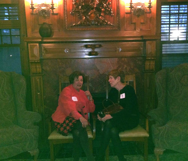 Friends and supporters of the YWCA Wege Sojourner House, Pat Waring and Joan Krause--who with Deb Bailey co-chaired the capital campaign to renovate and expand the emergency shelter--sit in front of the  fireplace in the former Wilcox  home with the family's hand-carved coat of arms above the mantel. 